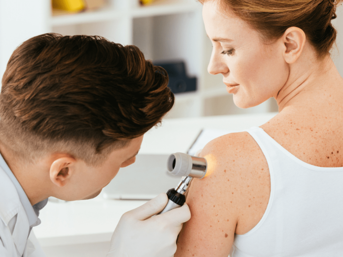 A dermatology provider giving a skin exam to a female patient.